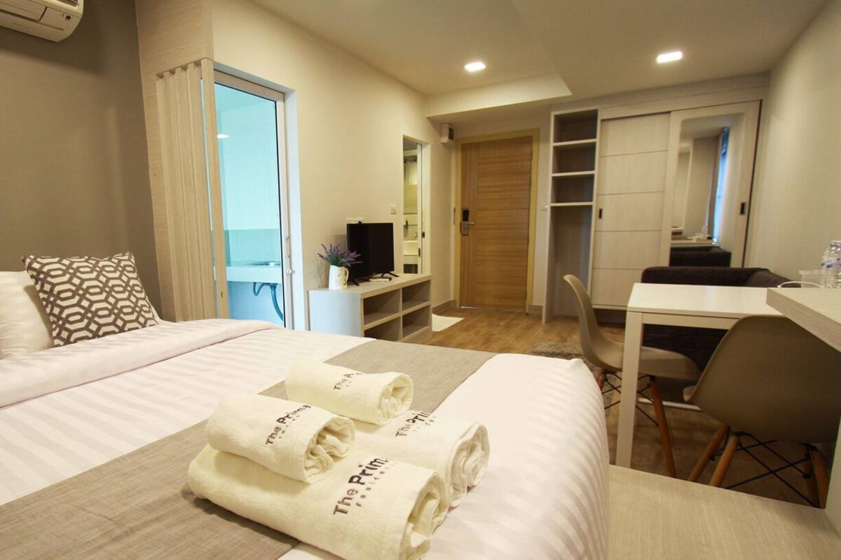 Una camera d'albergo con un letto, una scrivania, una sedia, una televisione e un armadio.