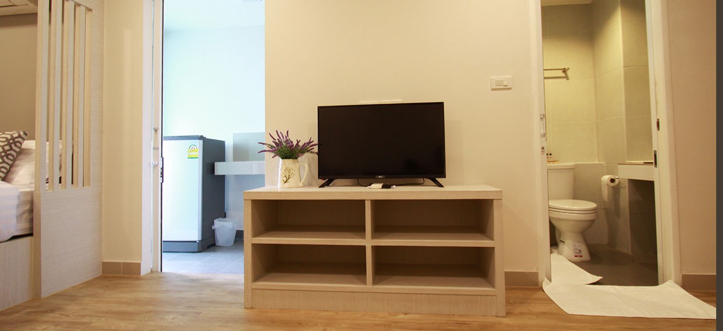 Ein Flur mit Fernseher auf einer Ablage, einem Mülleimer und einer Toilette im Hintergrund.