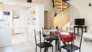 Una cocina moderna con armarios blancos, una mesa de comedor con sillas y una escalera en espiral.