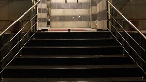 Un escalier menant à un ascenseur doté d’une porte en verre et de rampes métalliques.