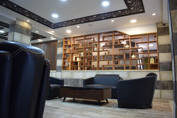 A modern lobby with a seating area, a decorative wooden shelving unit, and a stone accent wall.