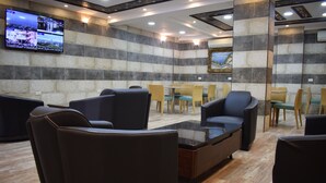 Un hall d’entrée avec des espaces où s’asseoir, un téléviseur à écran plat fixé au mur et un tableau encadré accroché au mur.