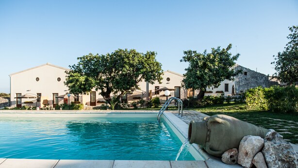 Una piscina con borde de piedra, un chorro de agua y una repisa de piedra.