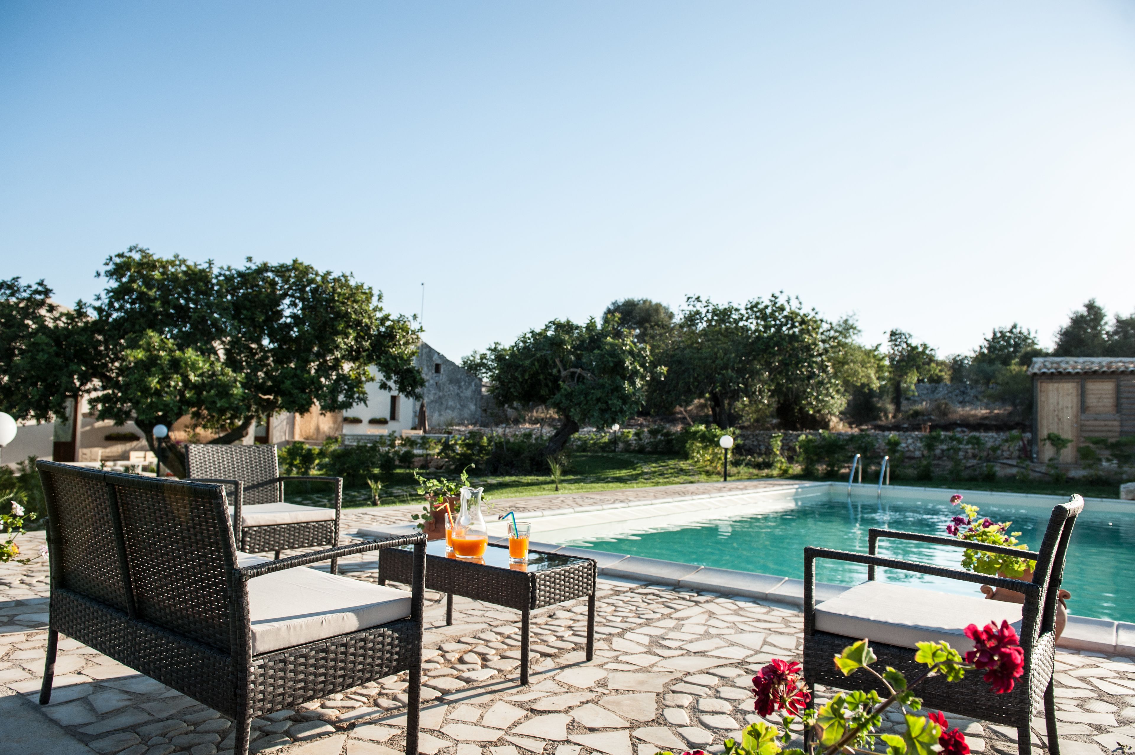 A poolside area with wicker furniture and a table with drinks.