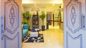 A foyer with a checkered floor, a blue sofa, a black coffee table, and a decorative ceiling. -  River Retreat Boutique Hotel (Siem Reap)
