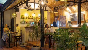 An outdoor cafe with tables and chairs, a bar area with bottles, and a menu board. -  River Retreat Boutique Hotel (Siem Reap)