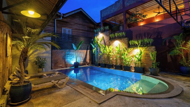 A swimming pool with surrounding potted plants and a wooden deck. -  River Retreat Boutique Hotel (Siem Reap)