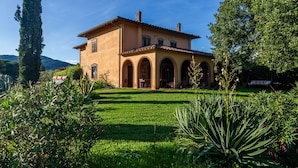 A two-story house with a garden in front. - Agriturismo Bio Fattoria Casetta (Gavorrano)
