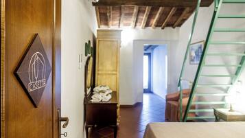Una habitación de hotel con puerta de madera, cama, armario, silla y una escalera.