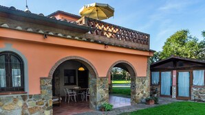 A building with a stone facade, arched entryways, and a patio area with outdoor seating. - Agriturismo Bio Fattoria Casetta (Gavorrano)