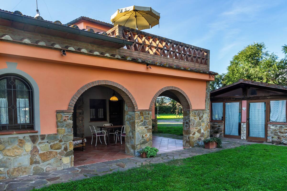 A building with a stone facade, arched entryways, and a patio area with outdoor seating.