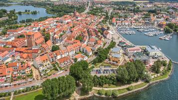 An aerial view of a town with a river, featuring historic buildings, a marina, and a park area.