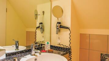 Une salle de bain équipée d’un lavabo, d’un miroir, d’un sèche-cheveux et de toilettes.