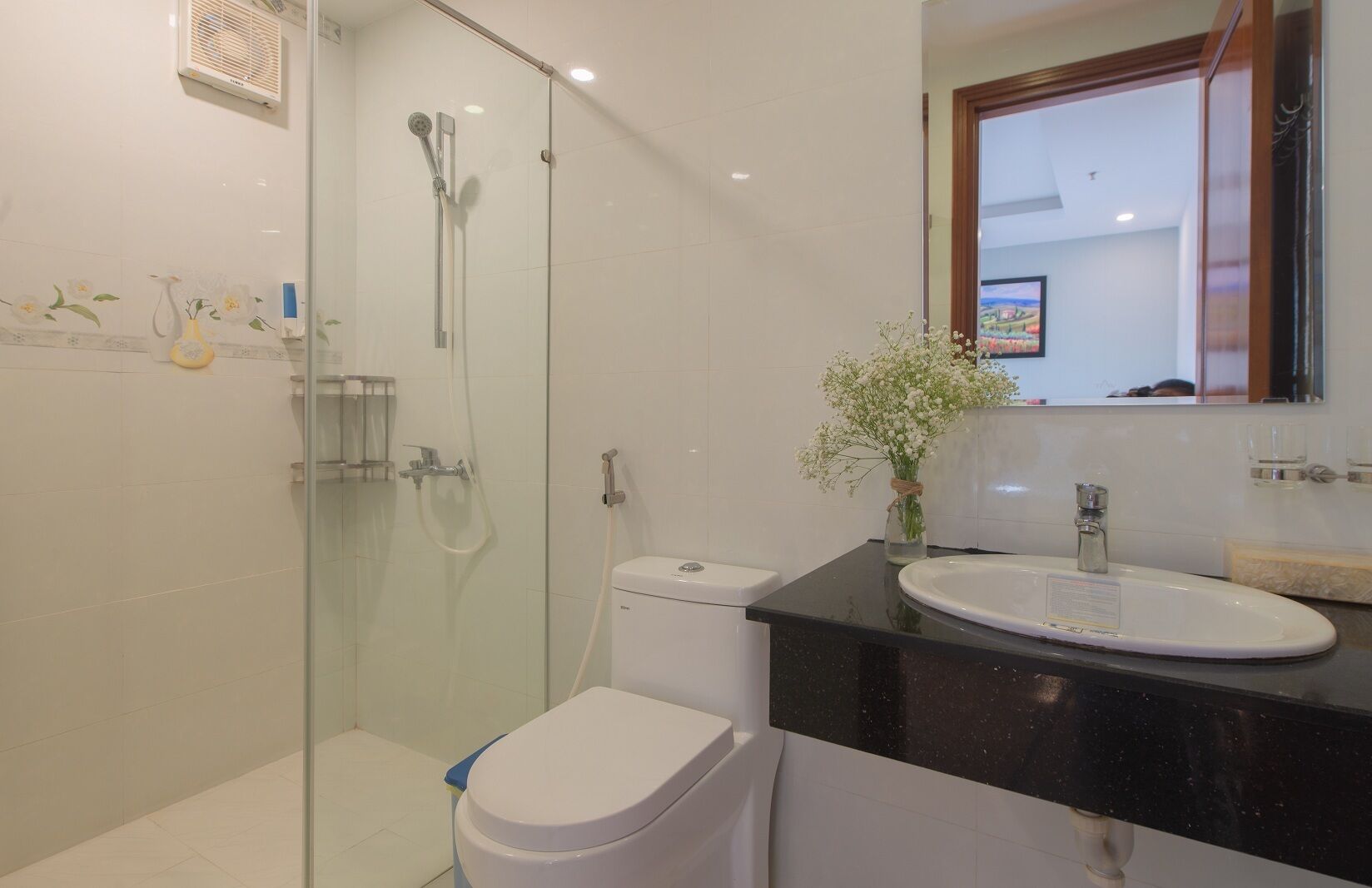 A modern bathroom with a glass-enclosed shower, a white toilet, and a black countertop with a sink.
