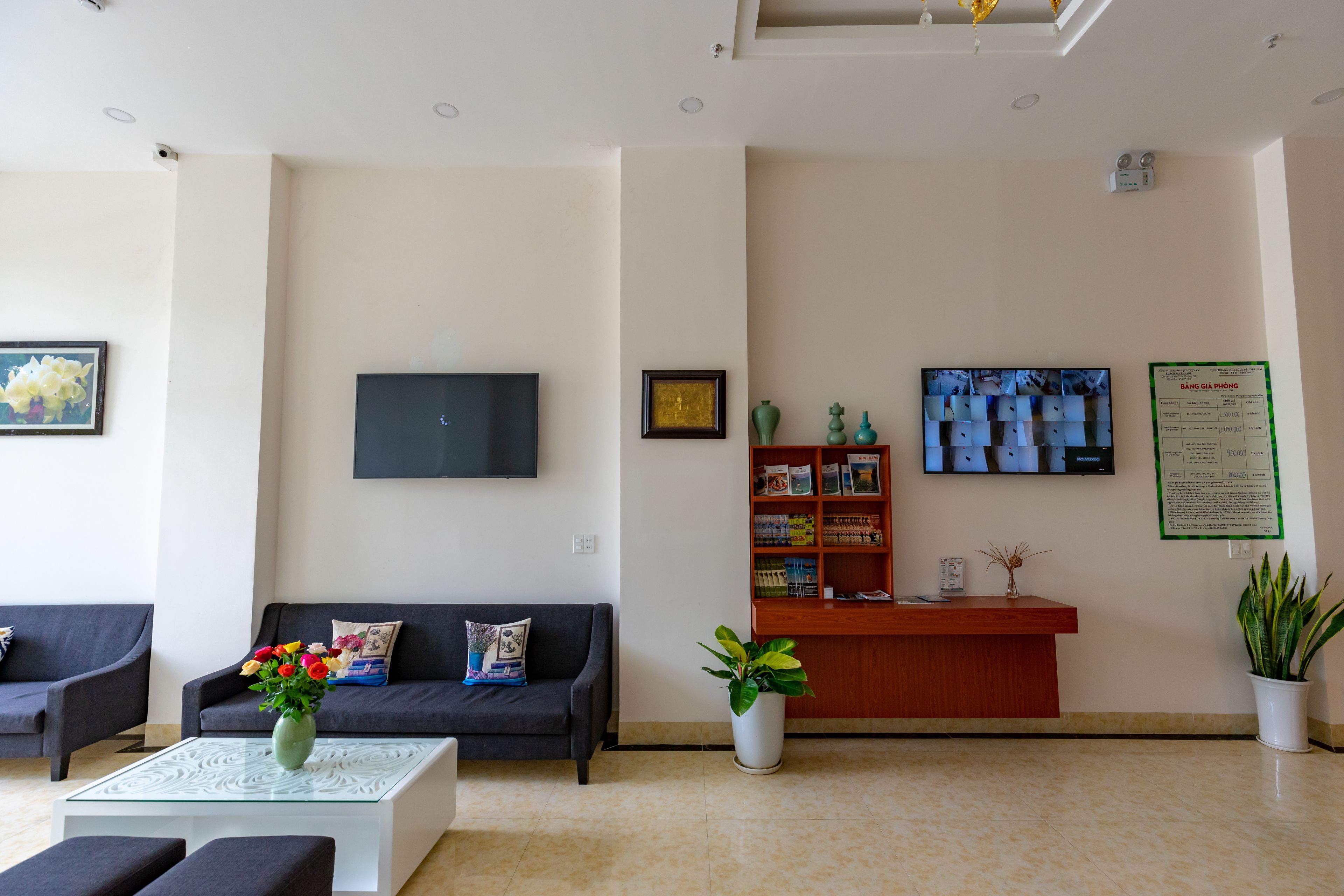 A reception area with a reception desk, a sofa, a coffee table, and a TV mounted on the wall.
