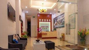 A hotel reception area with a reception desk, sofas, a coffee table, and a glass partition. - Canary Nha Trang Hotel (Bac Nha Trang)