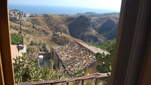 A view from a window overlooking a coastal landscape with terraced houses and a cactus garden. - Case Rurali Pentedattilo (Melito di Porto Salvo)
