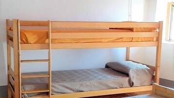 Ein Etagenbett mit einer Treppe, einer grauen Matratze und einem Kopfkissen.