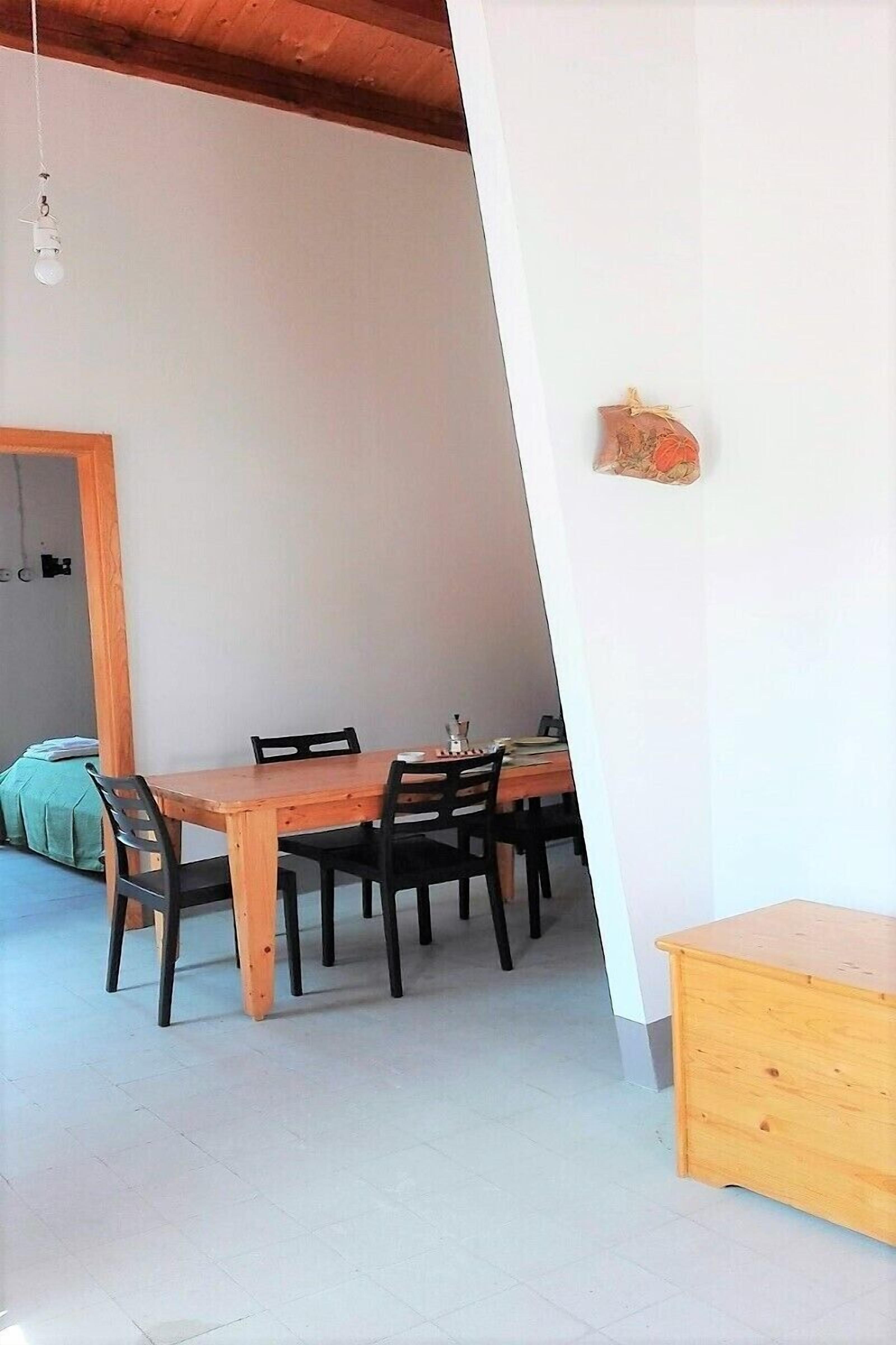 Un comedor con una mesa y sillas de madera, un pequeño aparador de madera y una lámpara colgante.