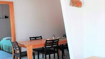 Un comedor con una mesa y sillas de madera, un pequeño aparador de madera y una lámpara colgante.