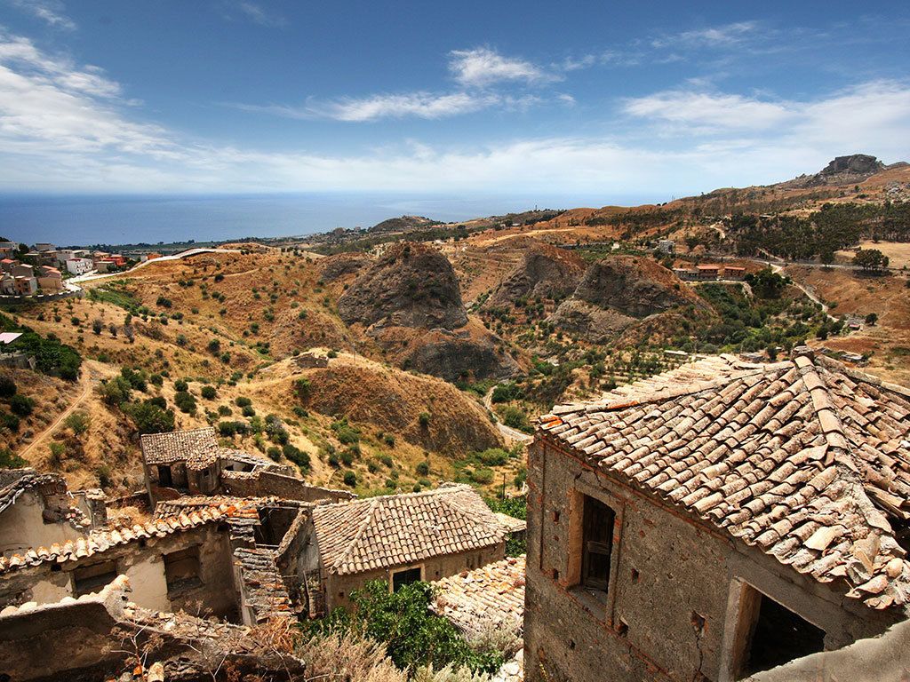 Un village rural caractérisé par ses bâtiments traditionnels en pierre et ses collines en terrasses.