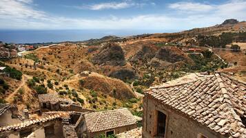 Un village rural caractérisé par ses bâtiments traditionnels en pierre et ses collines en terrasses.