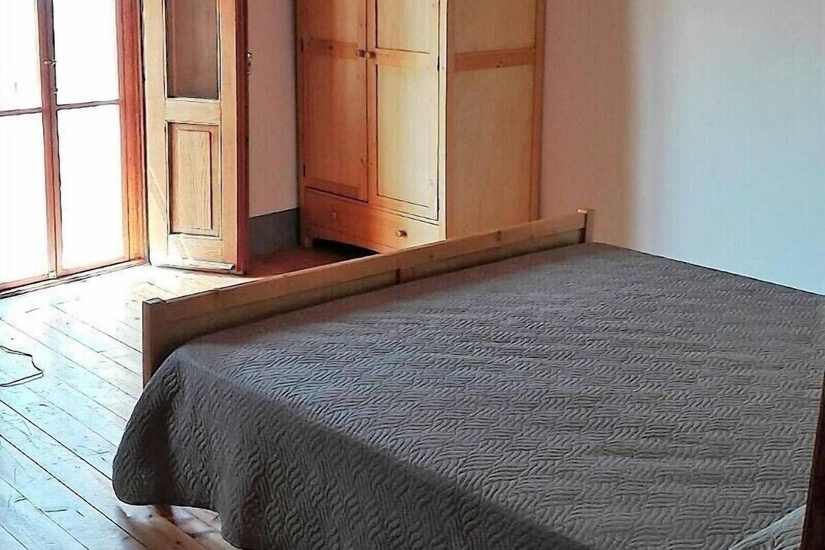 Un dormitorio con cama, armario de madera y ventana.