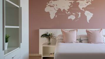Een slaapkamer met een wereldkaart aan de muur, een bed met kussens, een nachtkastje met een bloevas en een witte kast.