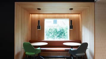 A modern interior with a wooden bench seating area, two chairs, and pendant lighting.