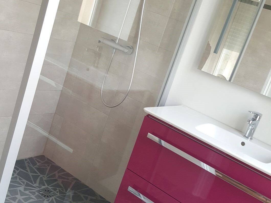 A bathroom with a shower, a sink, and a mirror.