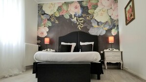 A bedroom with a large bed, two bedside tables with lamps, a nightstand, and a floral mural on the wall. - La Maison Blanche (Blaye)