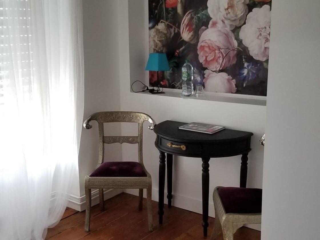 Una habitación con una silla, una mesita y un cuadro en la pared.