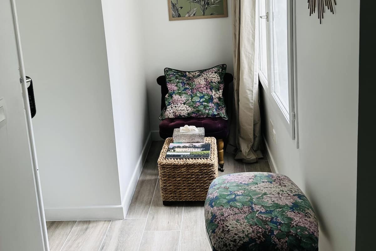 A hallway with a dark-colored bench, a wicker basket, and a floral-patterned ottoman.
