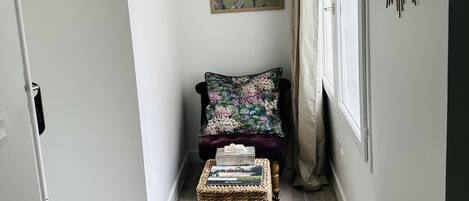 A hallway with a dark-colored bench, a wicker basket, and a floral-patterned ottoman.