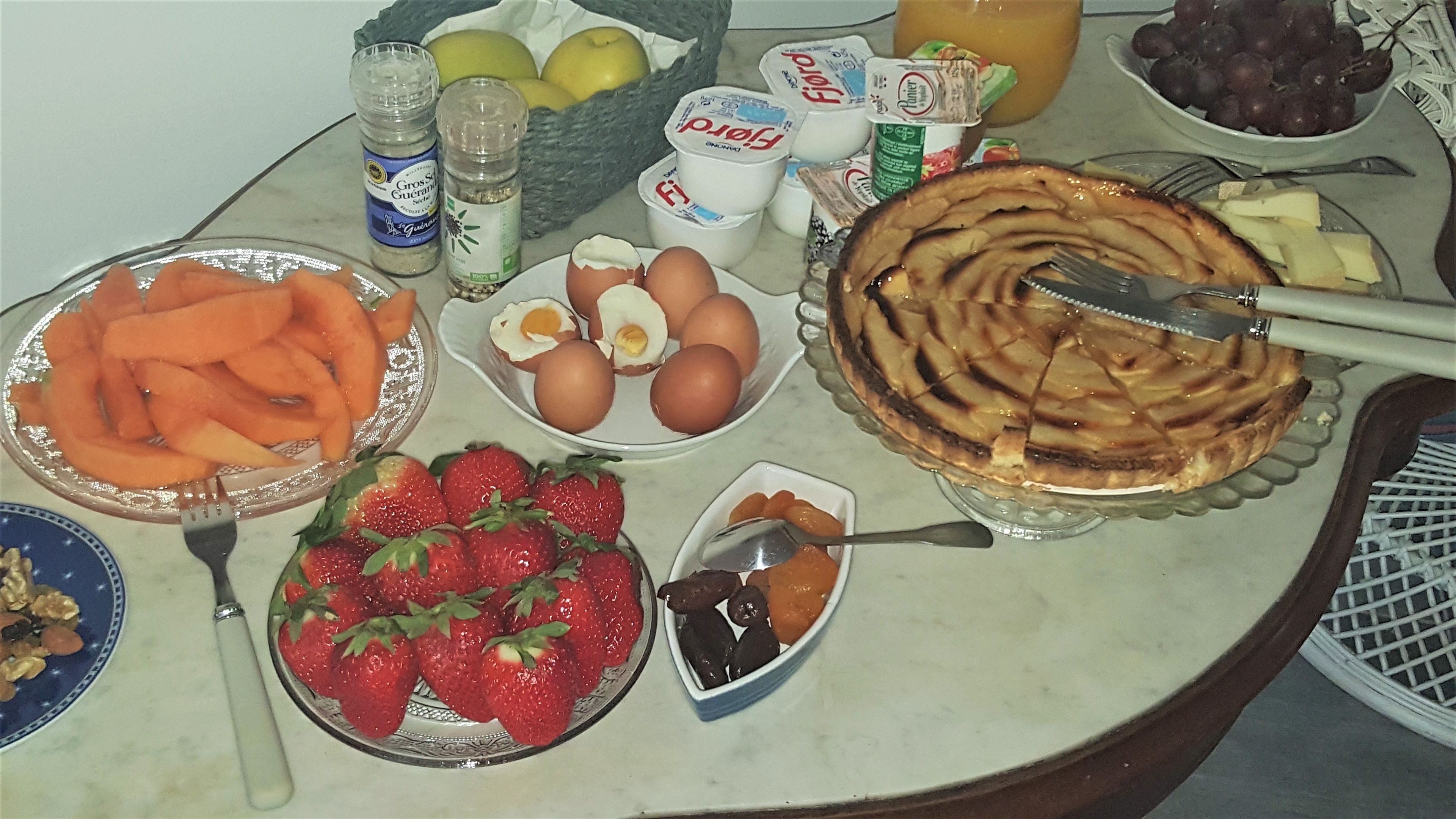 A breakfast table with various food items including eggs, strawberries, and a pie.
