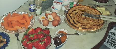 A breakfast table with various food items including eggs, strawberries, and a pie.