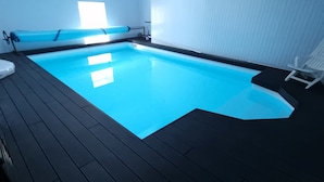 A swimming pool with a wooden deck, a bench, and a chair. - La Maison Blanche (Blaye)