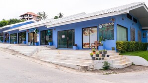 Un edificio azul con varias fachadas, que incluye una farmacia y un restaurante.