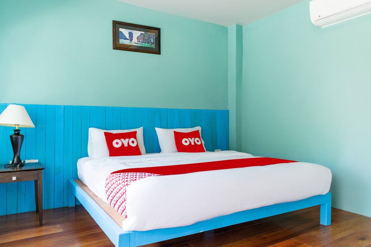 Ein Schlafzimmer mit einem Bett, einem Nachttisch, einer Lampe und einem gerahmten Bild an der Wand.