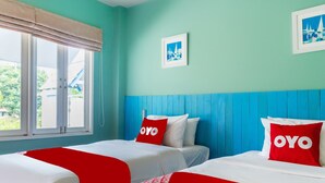 Habitación de hotel con dos camas, paredes color turquesa y ventana con vista al exterior.