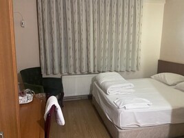 Una habitación de hotel con una cama, una silla, un radiador y una cortina.