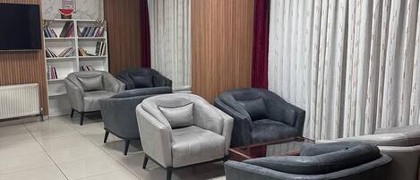 A modern living room with grey sofas, a coffee table, and a bookshelf.