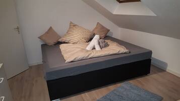 Ein modernes Schlafzimmer mit einem Bett, Kissen und einem kleinen Stofftier.