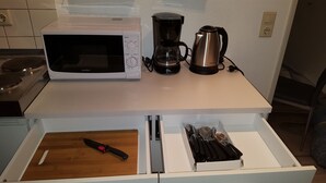 Eine Küche mit Mikrowelle, Kaffeemaschine und einer Schublade mit Besteck.