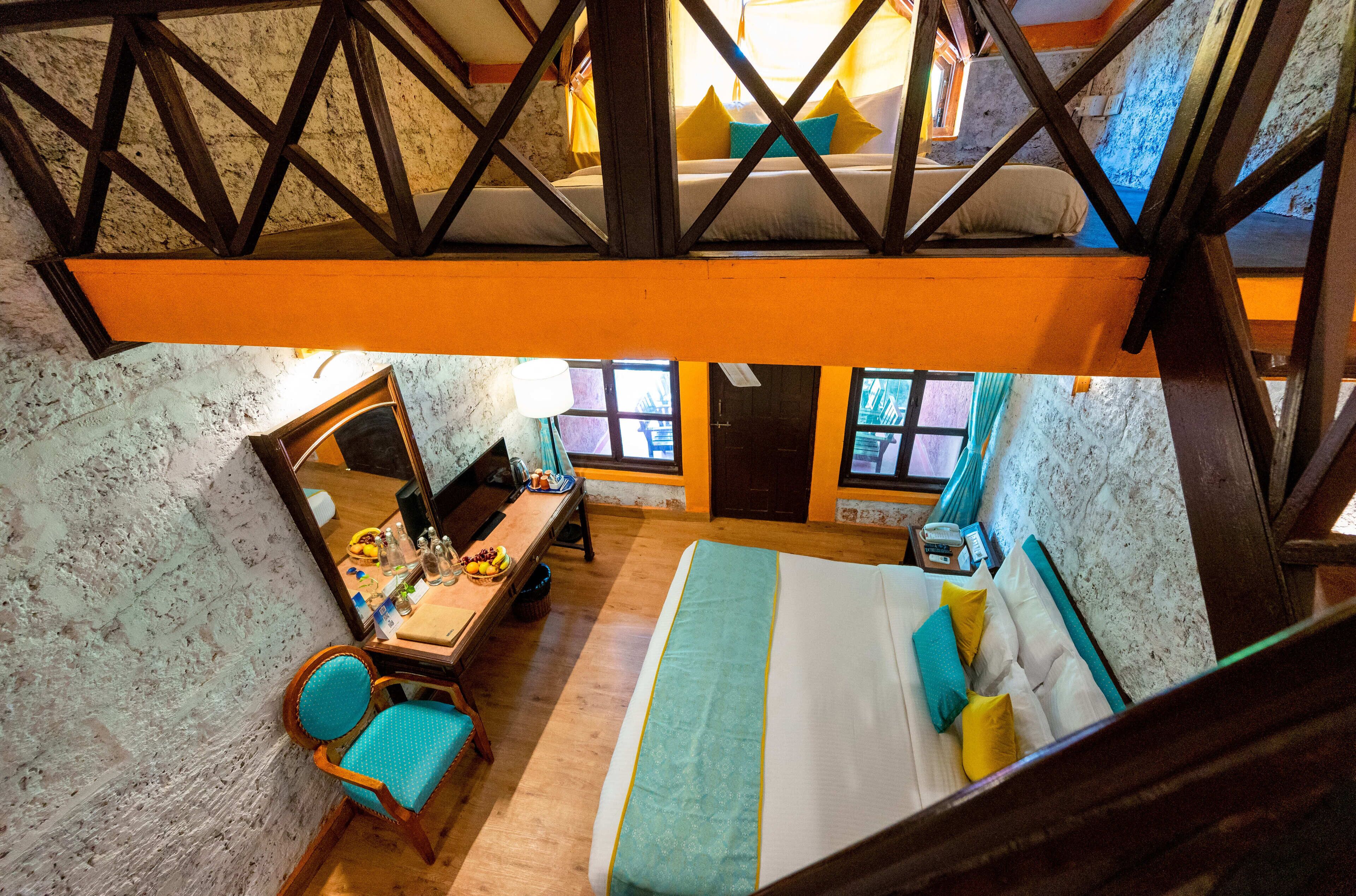 Een kamer met hoge plafonds, een bed, een bureau en een stoel.
