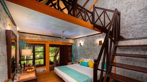 Ein Schlafzimmer mit einem hölzernen Bett, einem Schreibtisch mit Lampe, einem Fenster mit Vorhängen und einer Treppe.