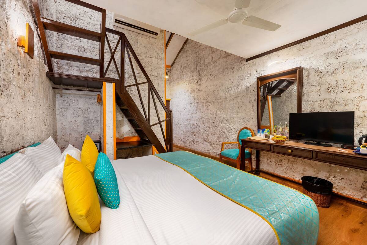 Une chambre à coucher avec un lit, un bureau, une télévision et un escalier.