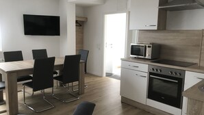Cocina moderna con microondas, horno y armarios blancos. Cuenta con una zona de comedor con mesa y sillas.