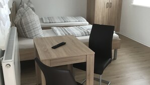 Un espacio habitable compacto con cama, una mesita, dos sillas, un armario y un radiador.