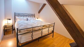 Een slaapkamer met een bed, nachtkastjes en een schuine plafond.